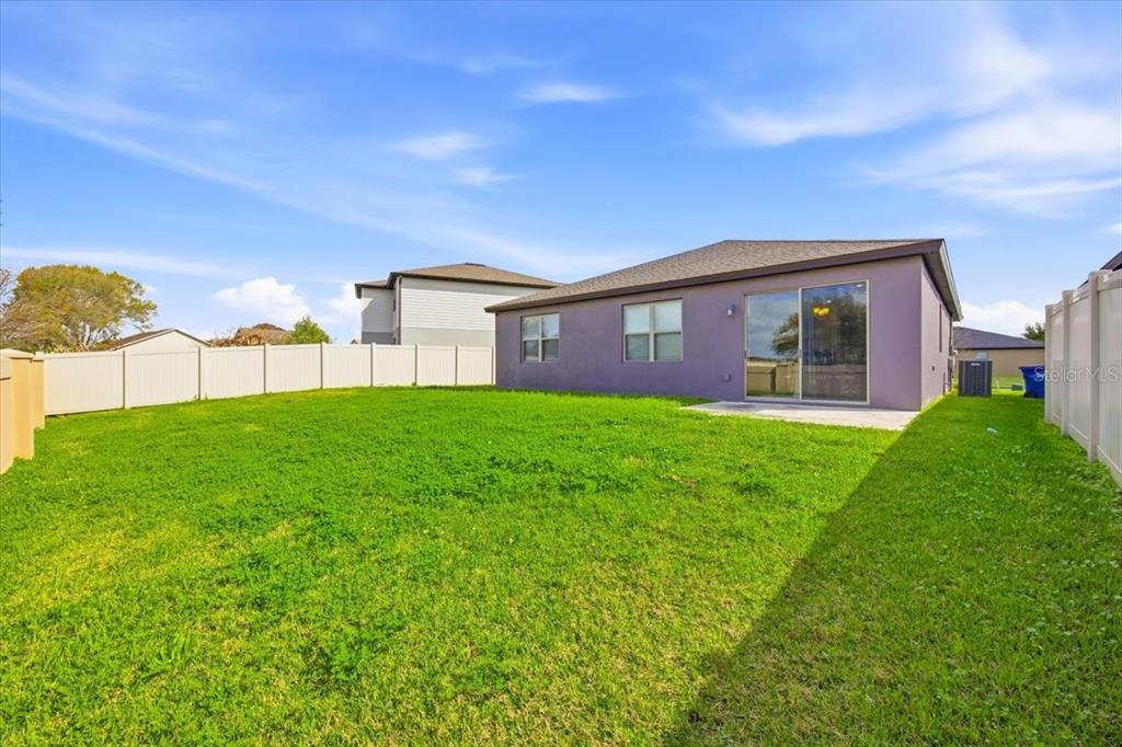 The backyard of a house features a lawn, a patio, and a white vinyl fence — 1917 CAYMAN COVE CIRCLE, ST CLOUD, FL
