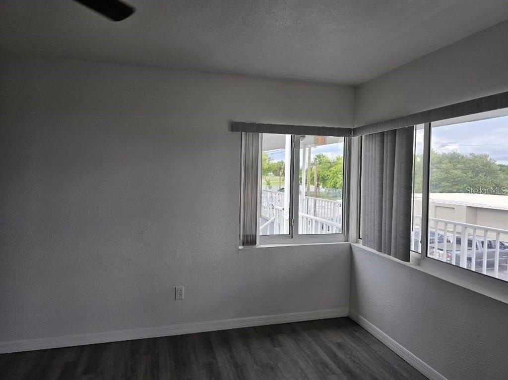 An empty room with gray wood-look flooring, white walls, and windows overlooking an outdoor walkway — 800 N FISKE BOULEVARD UNIT 714, COCOA, FL