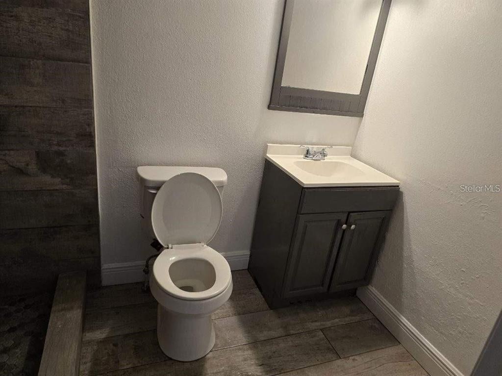 A bathroom features a toilet, a gray vanity with a sink, and wood-look tile flooring — 800 N FISKE BOULEVARD UNIT 714, COCOA, FL