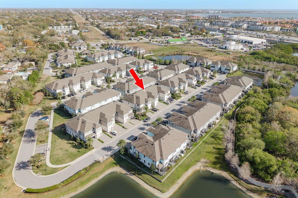 An aerial view shows a multi-unit residential complex with a red arrow pointing to a building — 2442 FOGGY CREEK CIRCLE, CLEARWATER, FL
