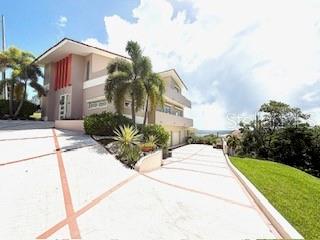 A multi-story house with a large concrete driveway and palm trees sits on a hill — 1 SHELL CASTLE CLUB UNIT 86, HUMACAO, PR