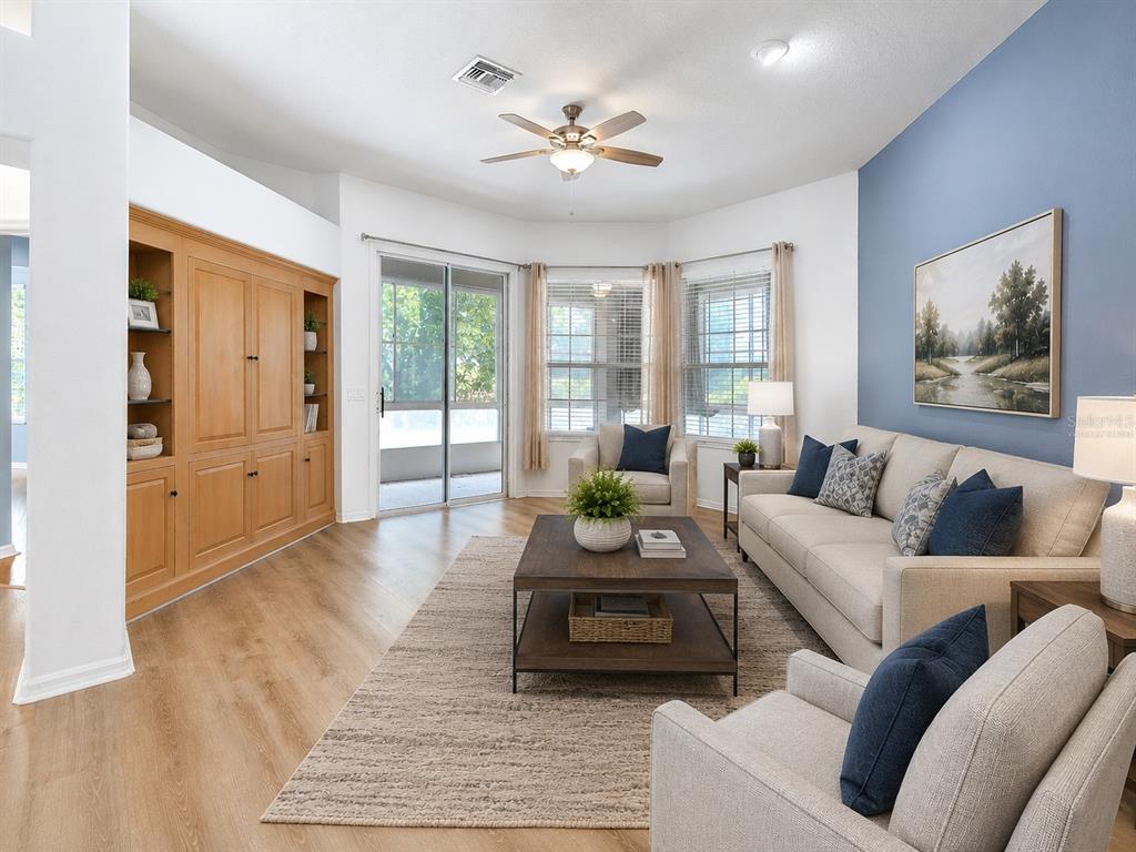 A living room features light wood flooring, a blue accent wall, and built-in wooden cabinetry — 6200 TOPSAIL ROAD, LADY LAKE, FL