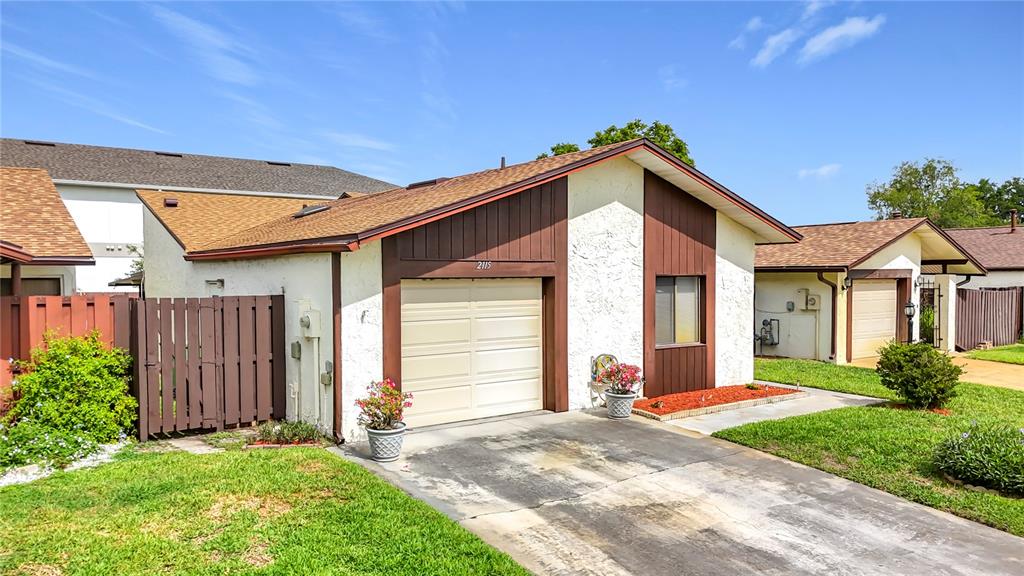 A single-story house with a white stucco facade, brown trim, and a concrete driveway — 2115 KINGS CROSSING SW, WINTER HAVEN, FL