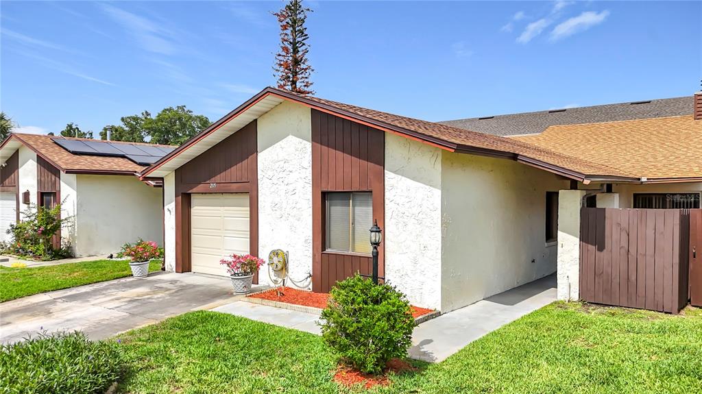 A single-story house exterior features a garage, brown vertical siding, and a tan stucco facade — 2115 KINGS CROSSING SW, WINTER HAVEN, FL