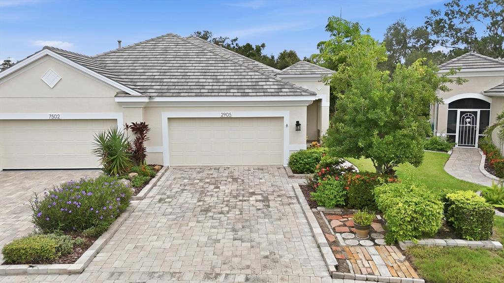A beige house with a tiled roof, two garage doors, and a paved driveway — 2905 TRUSTEE AVENUE, SARASOTA, FL