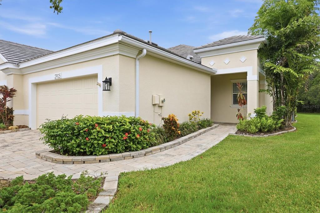 A beige house exterior features a paved driveway, a garage, and a landscaped walkway — 2905 TRUSTEE AVENUE, SARASOTA, FL