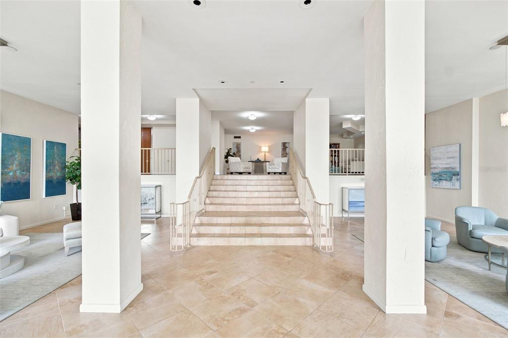A spacious lobby features a central staircase, tile flooring, and seating areas on both sides — 707 S GULFSTREAM AVENUE UNIT 207, SARASOTA, FL