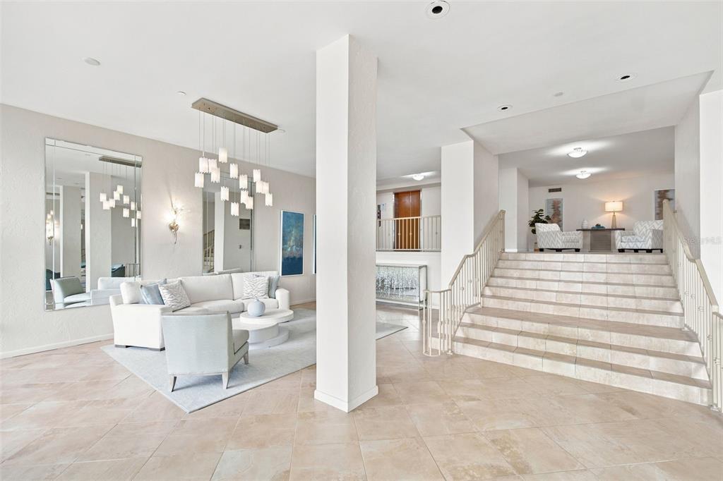 A living area with a white sofa and stairs leading to an upper level — 707 S GULFSTREAM AVENUE UNIT 207, SARASOTA, FL
