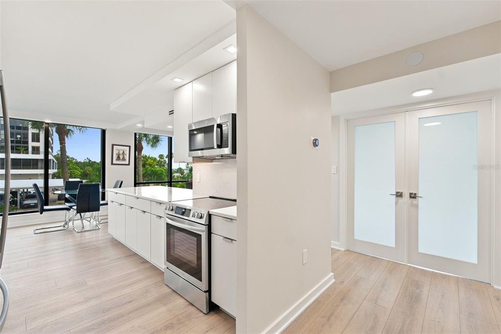 A modern kitchen with white cabinets and stainless steel appliances overlooks a dining area — 707 S GULFSTREAM AVENUE UNIT 207, SARASOTA, FL