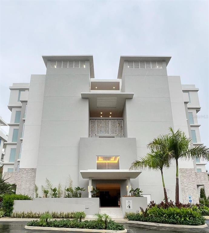 The exterior of a modern, multi-story building features a central entrance with decorative metal panels — Ocean Drive PH FOUR SEASONS PRIVATE RESIDENCES UNIT 4501, RIO GRANDE, PR