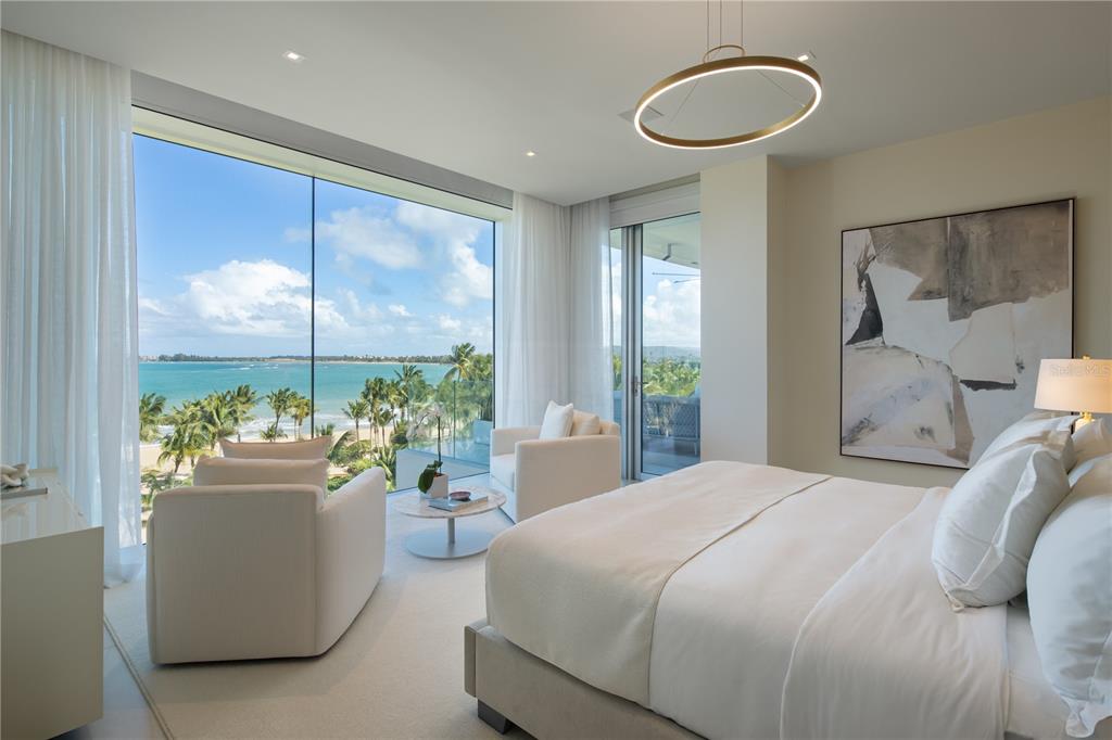 A modern bedroom features a large bed, two armchairs, and floor-to-ceiling windows overlooking the ocean — Ocean Drive PH FOUR SEASONS PRIVATE RESIDENCES UNIT 4501, RIO GRANDE, PR