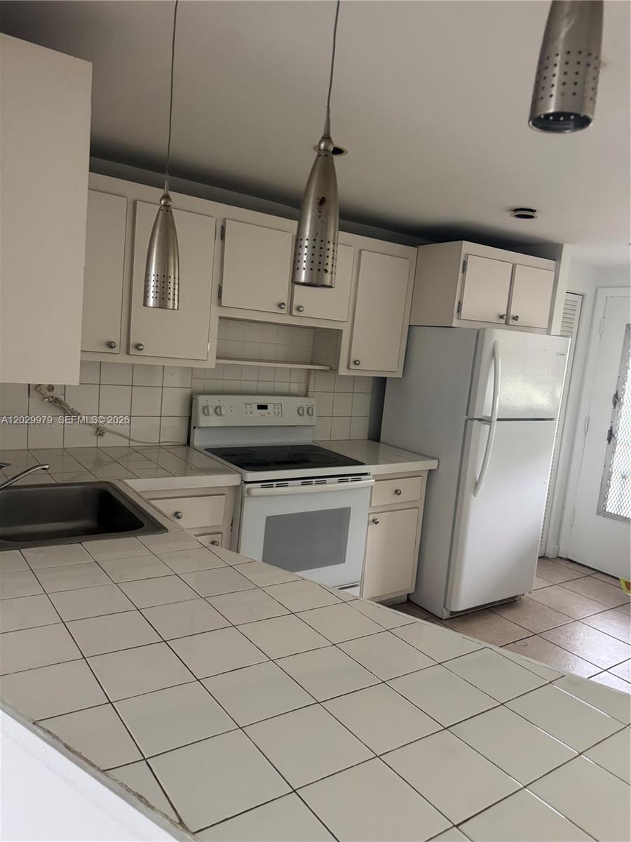 A kitchen features white tiled countertops, white cabinets, a white stove, and a white refrigerator — 1710 NE 191st St # 3, Miami FL 33179, MIAMI, FL