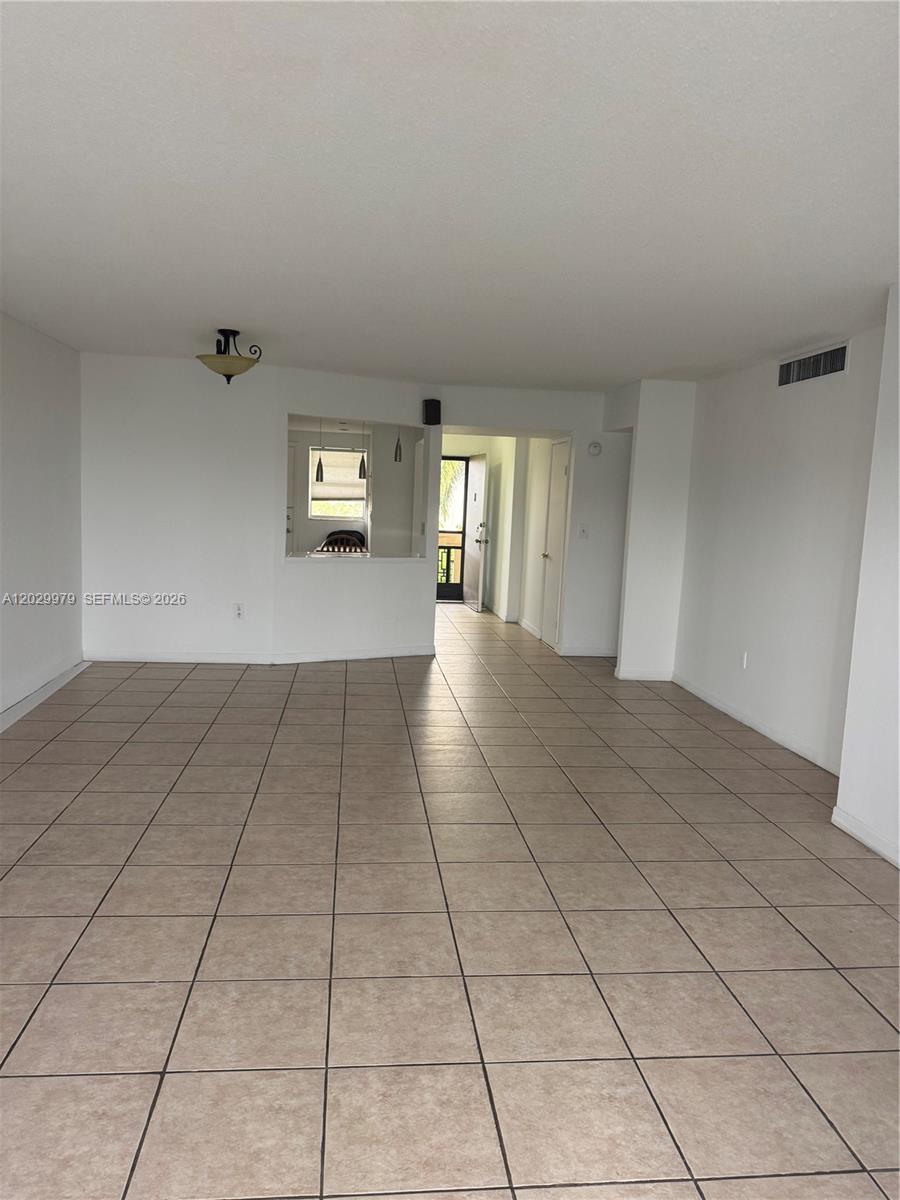 An empty room features beige floor tiles, white walls, and a pass-through window — 1710 NE 191st St # 3, Miami FL 33179, MIAMI, FL
