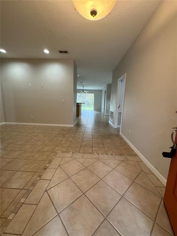 An entryway with tan tile flooring leads into an open-concept living area and kitchen — 10360 SANDY MARSH LANE, ORLANDO, FL