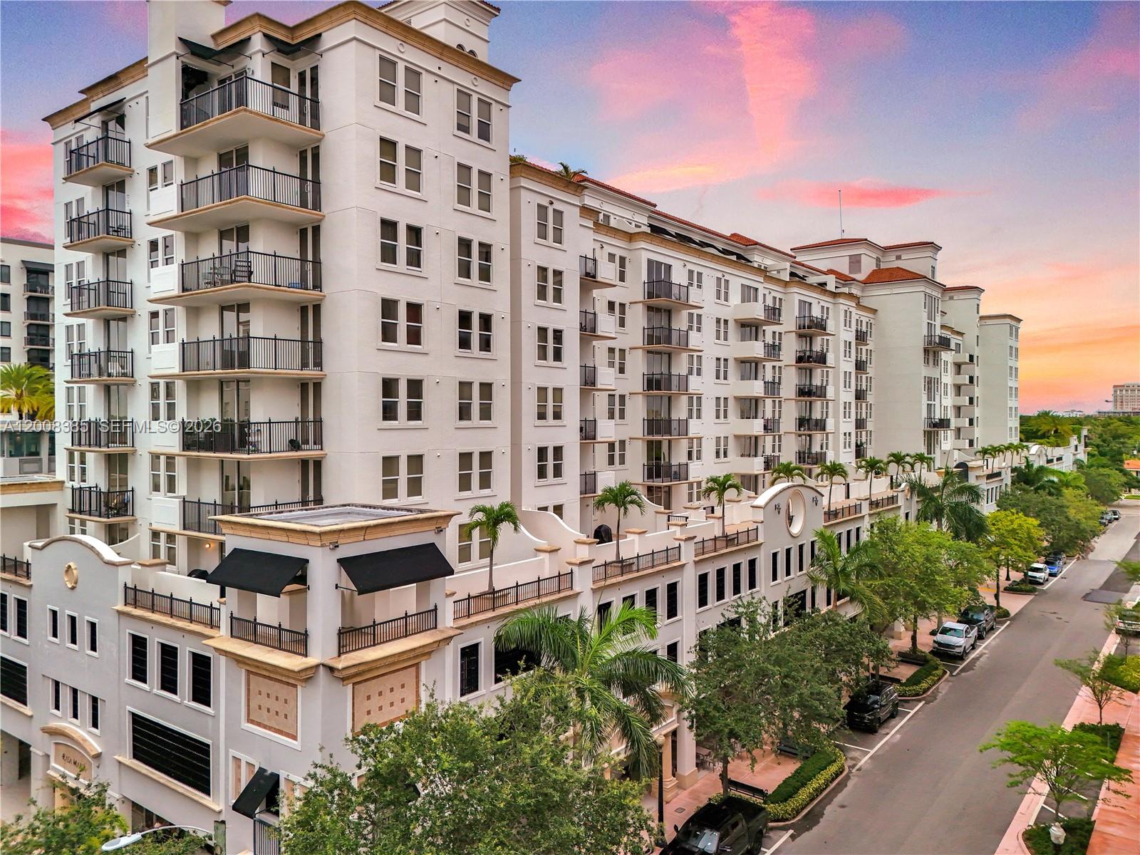 An exterior view of a multi-story apartment building with balconies and palm trees at sunset — 4100 Salzedo St # 411, Coral Gables FL 33146, CORAL GABLES, FL