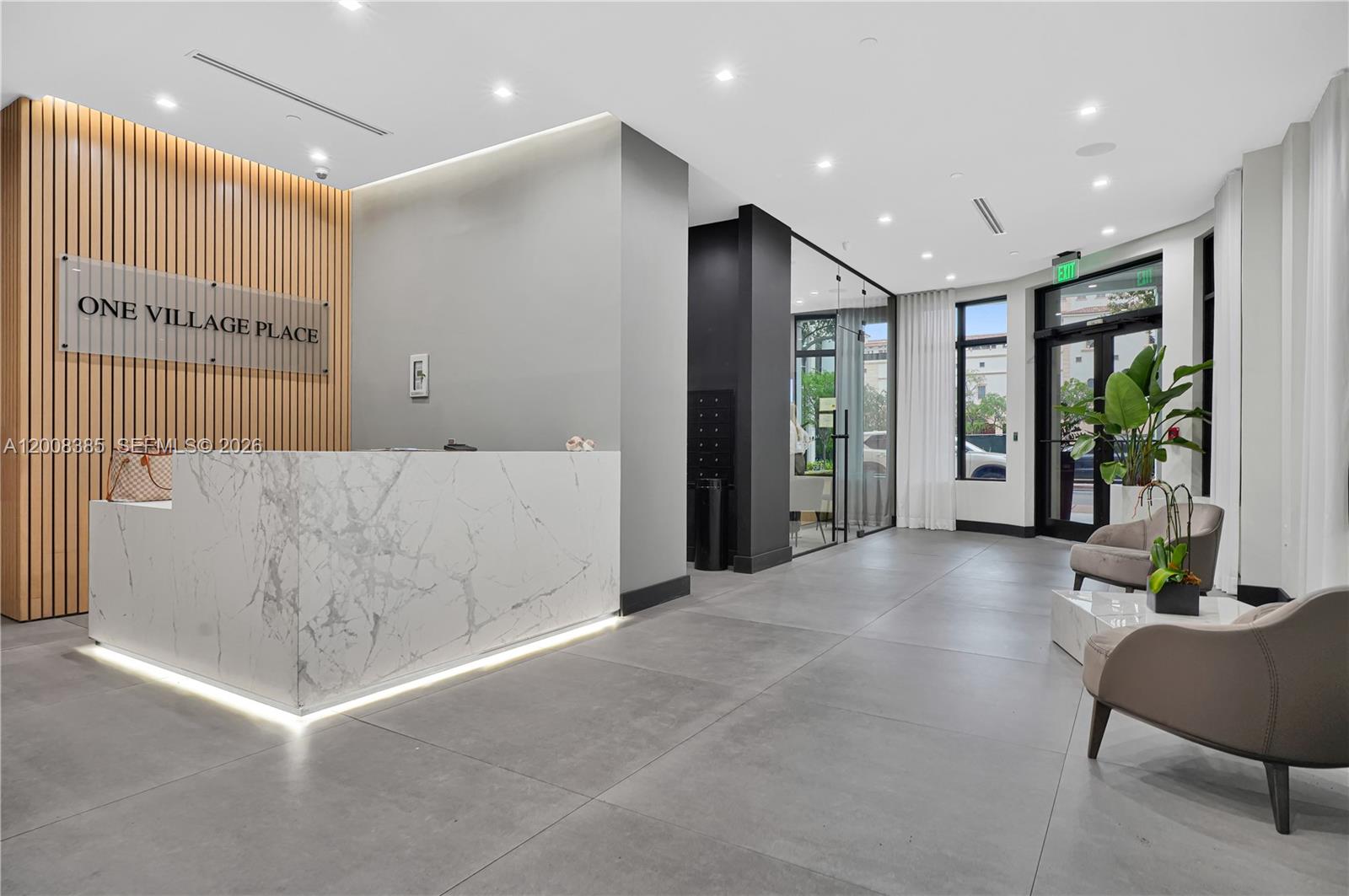 A modern lobby features a marble reception desk, wood-slat wall, and gray tile flooring — 4100 Salzedo St # 411, Coral Gables FL 33146, CORAL GABLES, FL