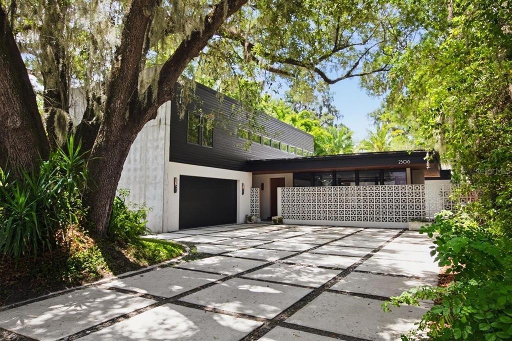 A modern two-story home with a concrete driveway, black siding, and a decorative breeze block wall — 2506 WOODSIDE AVENUE, ORLANDO, FL