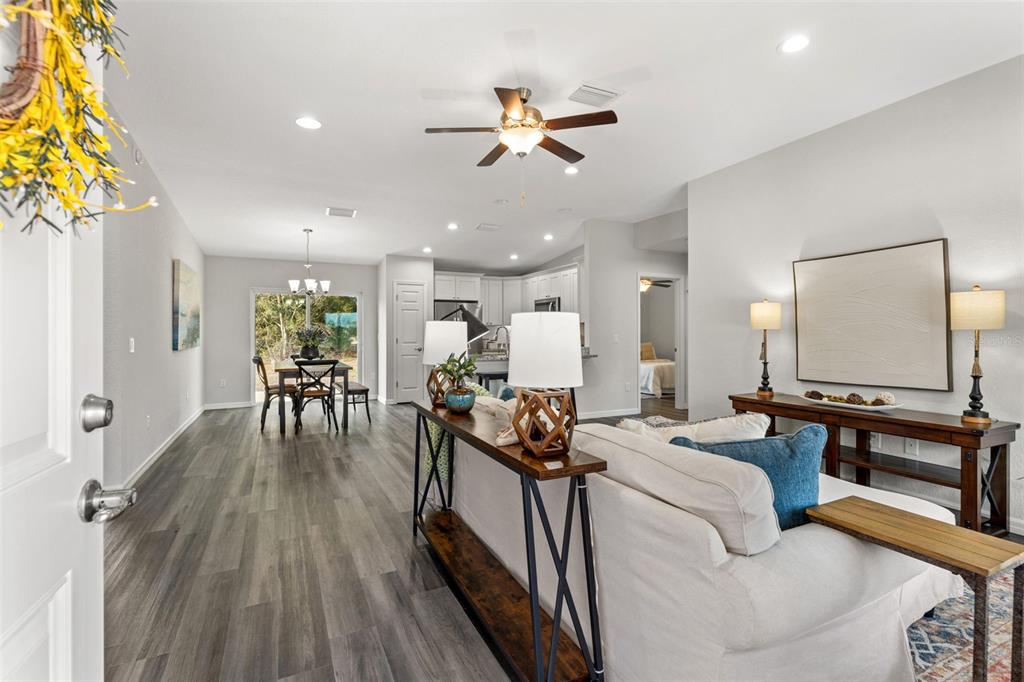 An open-concept living and dining area features gray wood-look flooring and a ceiling fan — 13920 SE 33RD COURT, SUMMERFIELD, FL