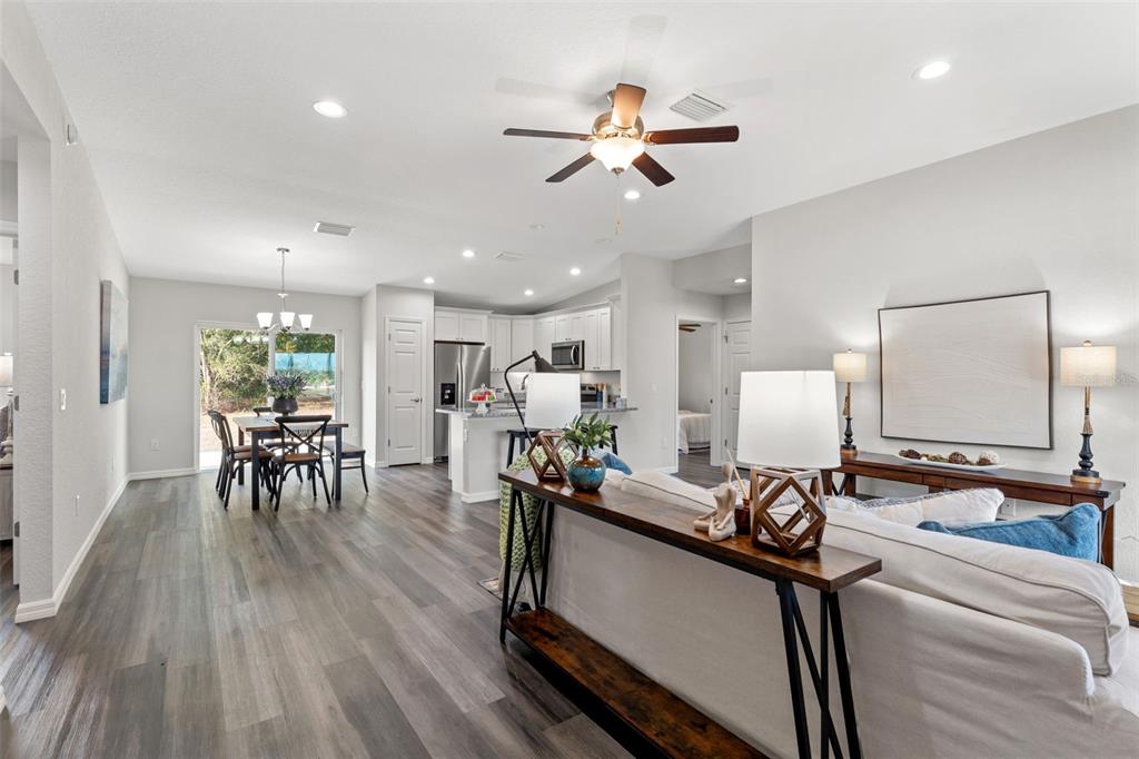 An open-concept living and dining area features wood-look flooring, a kitchen island, and recessed lighting — 13920 SE 33RD COURT, SUMMERFIELD, FL