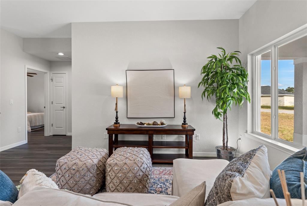 A living room features a wooden console table, two lamps, textured ottomans, and a potted plant — 13920 SE 33RD COURT, SUMMERFIELD, FL