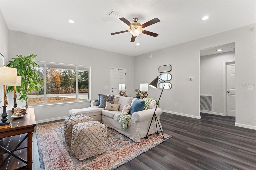 A living room features a white sectional sofa, two textured ottomans, and a large window — 13920 SE 33RD COURT, SUMMERFIELD, FL