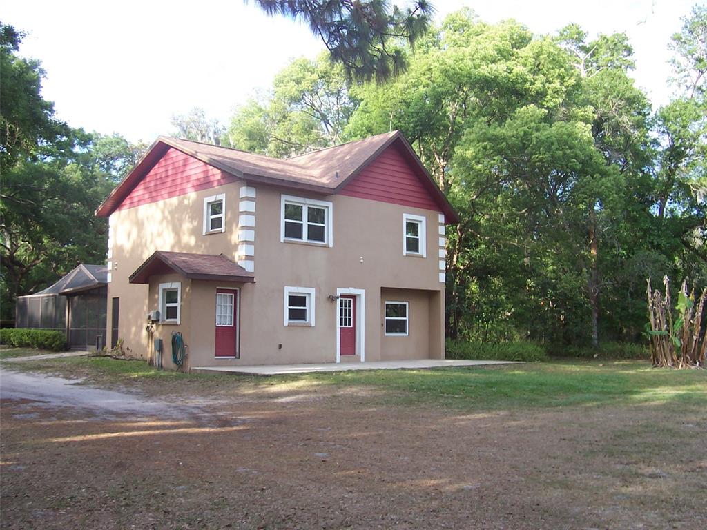 A two-story house with tan stucco walls, red trim, and a brown shingled roof — 37544 TUCKER ROAD, ZEPHYRHILLS, FL