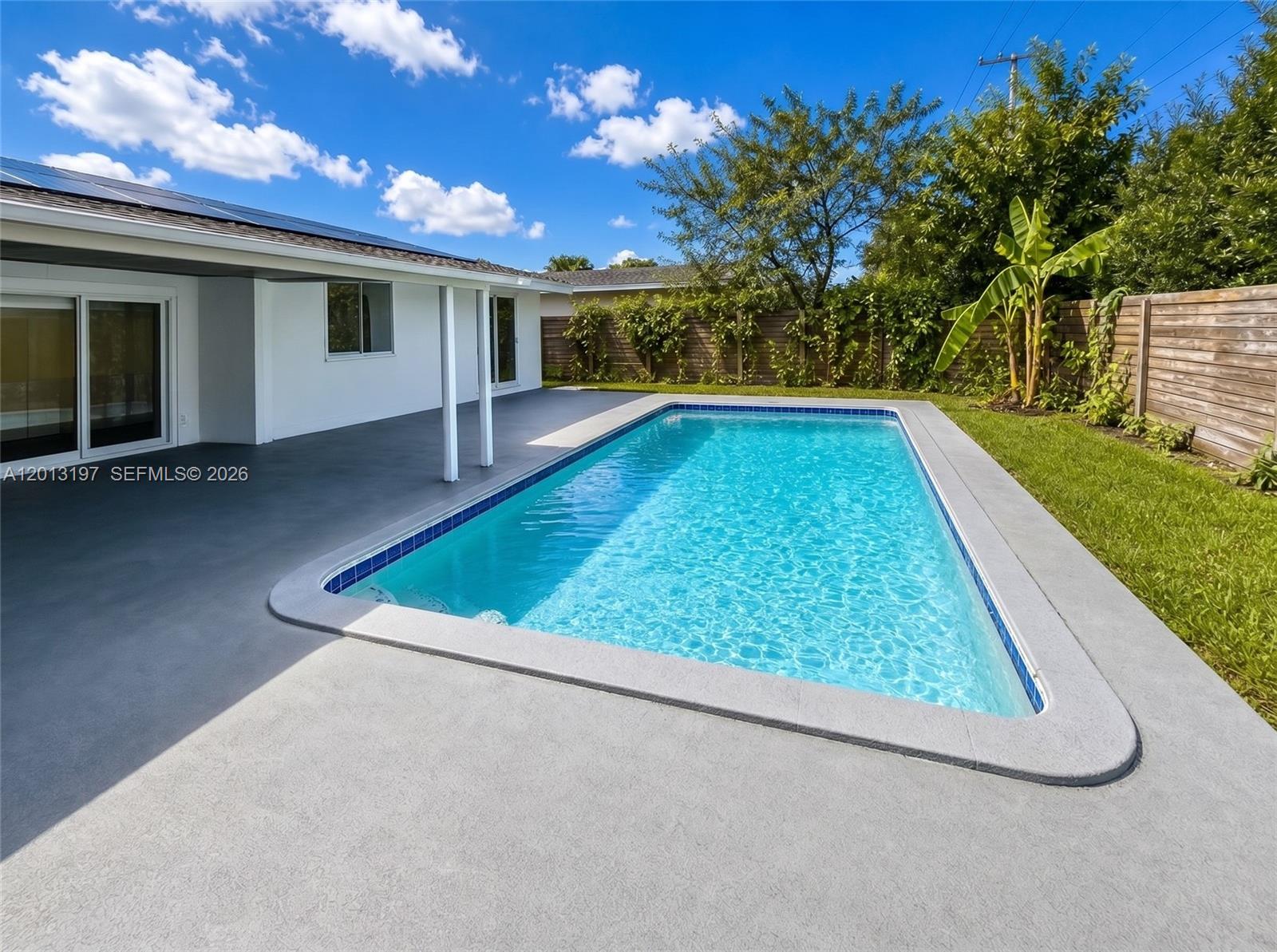 A rectangular swimming pool sits on a concrete patio beside a white house — 21335 NE 19th Ct, Miami FL 33179, MIAMI, FL
