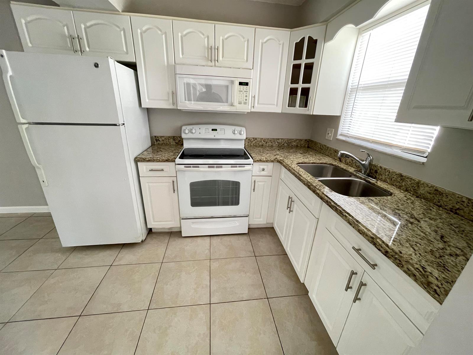 A kitchen features white cabinets, granite countertops, a white refrigerator, and a white stove — 5806 Channel Drive, FL 33463, FL