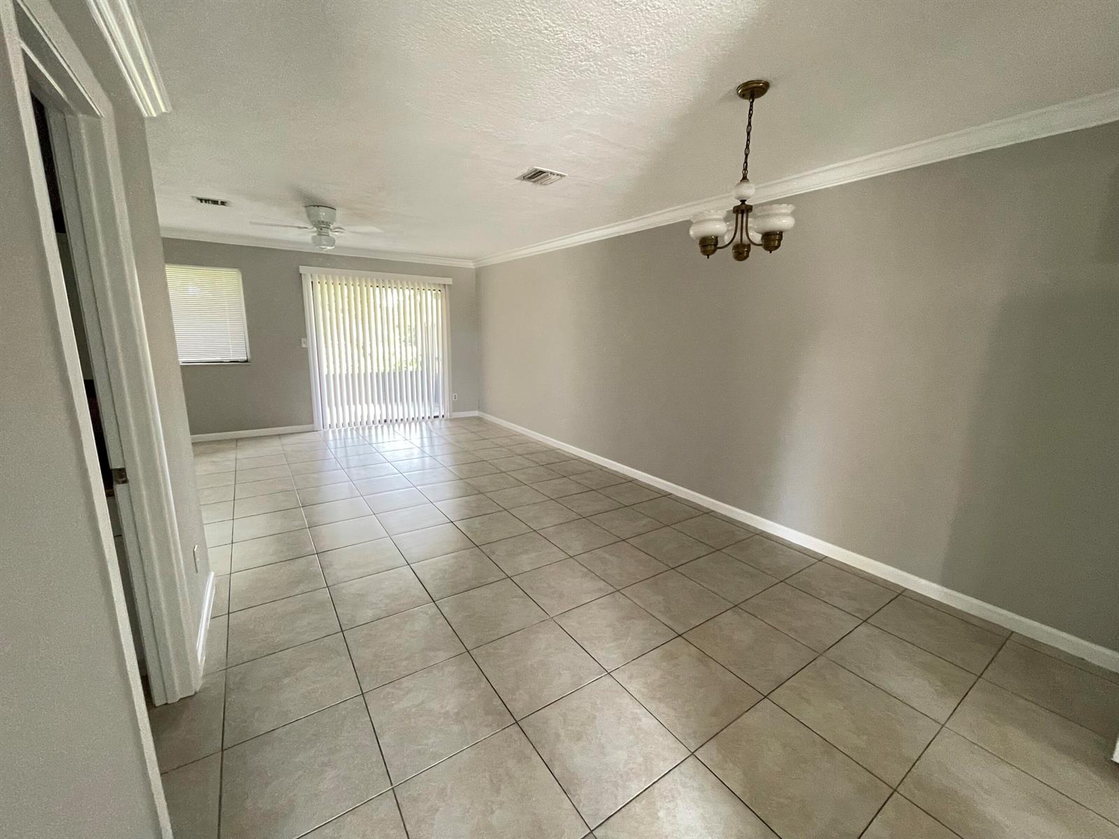 An open living area features light gray walls, large beige floor tiles, and a chandelier — 5806 Channel Drive, FL 33463, FL