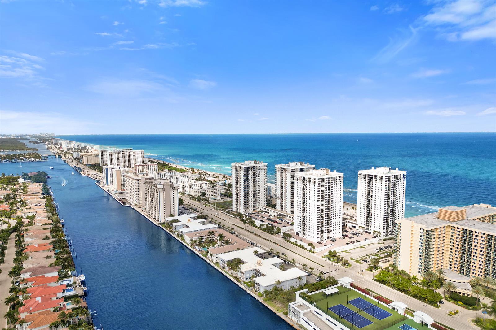 An aerial view shows high-rise apartment buildings along a canal and the ocean coastline — 2301 S Ocean Drive # 1408, Hollywood FL 33019, HOLLYWOOD, FL
