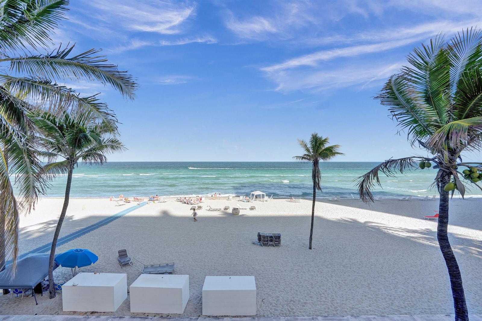 A view of a sandy beach with palm trees, lounge chairs, and the ocean — 2301 S Ocean Drive # 1408, Hollywood FL 33019, HOLLYWOOD, FL