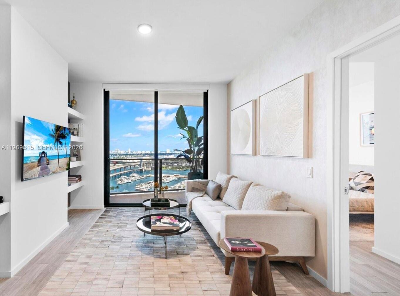 A modern living room features a white sofa, glass coffee tables, and a harbor view — 398 NE 5th St # 3811, Miami FL 33132, MIAMI, FL