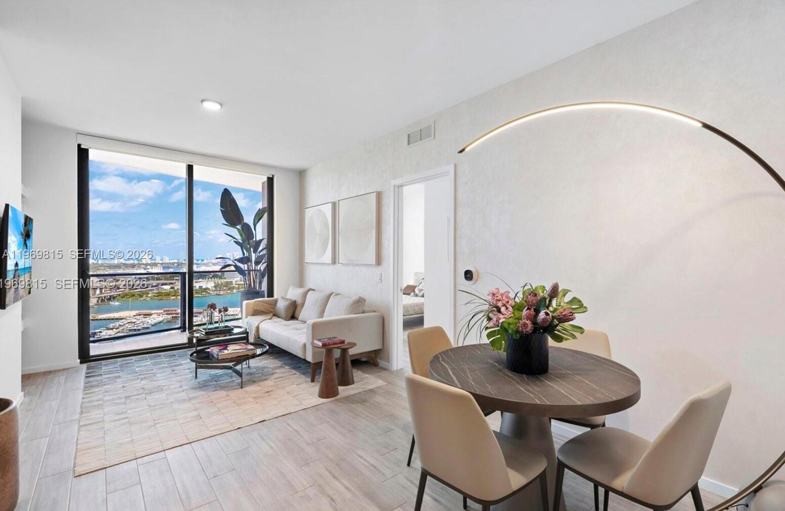 A modern living and dining area features floor-to-ceiling windows with a harbor view — 398 NE 5th St # 3811, Miami FL 33132, MIAMI, FL