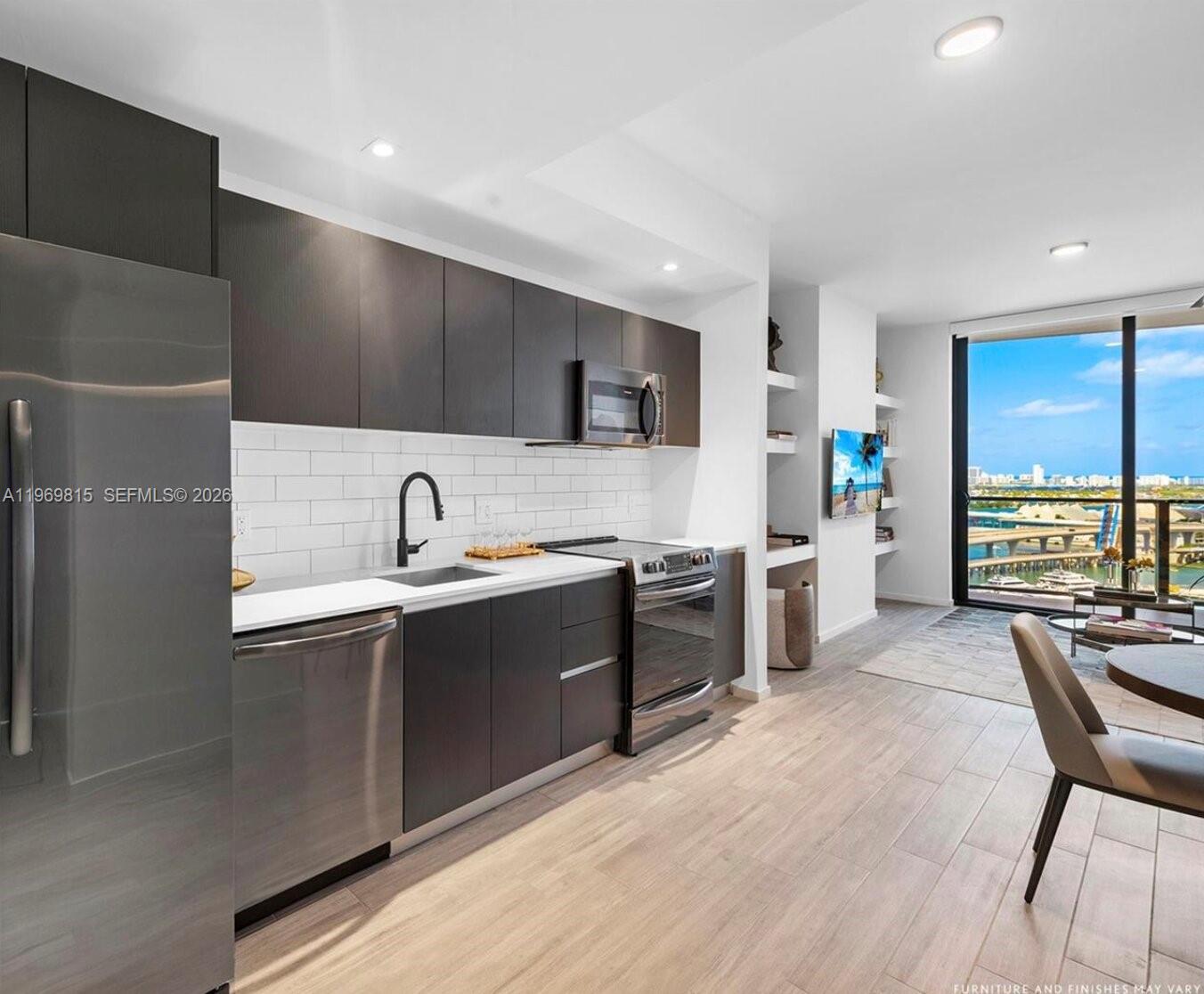 A modern kitchen with dark cabinetry, stainless steel appliances, and a view of the water — 398 NE 5th St # 3811, Miami FL 33132, MIAMI, FL