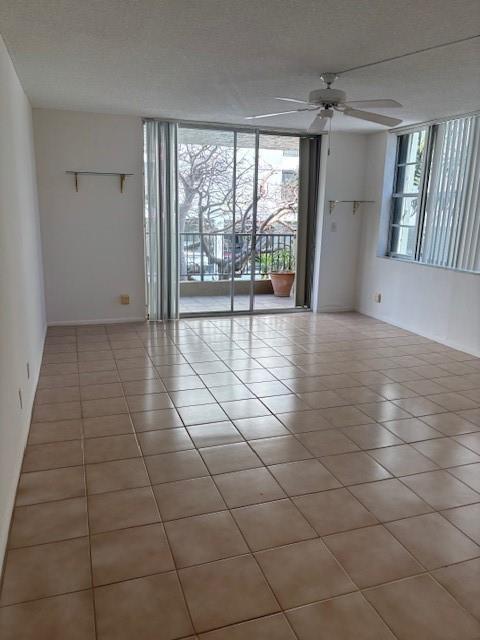 An empty living room features beige tile flooring, a ceiling fan, and sliding glass balcony doors — 1421 S Ocean Boulevard # 218, Pompano Beach FL 33062, POMPANO BEACH, FL