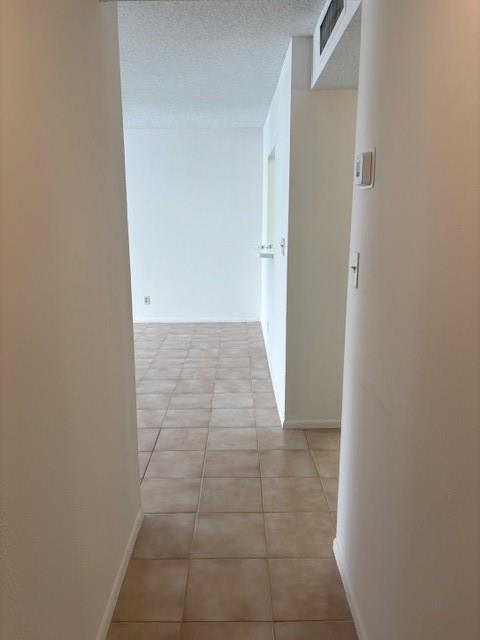 A view through a hallway with beige tile flooring leading into a bright, empty room — 1421 S Ocean Boulevard # 218, Pompano Beach FL 33062, POMPANO BEACH, FL