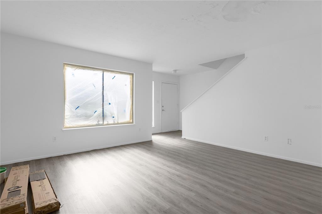 An empty room with white walls, gray wood-look flooring, and a window covered in plastic — 4025 BILLINGSGATE ROAD UNIT 2004, ORLANDO, FL