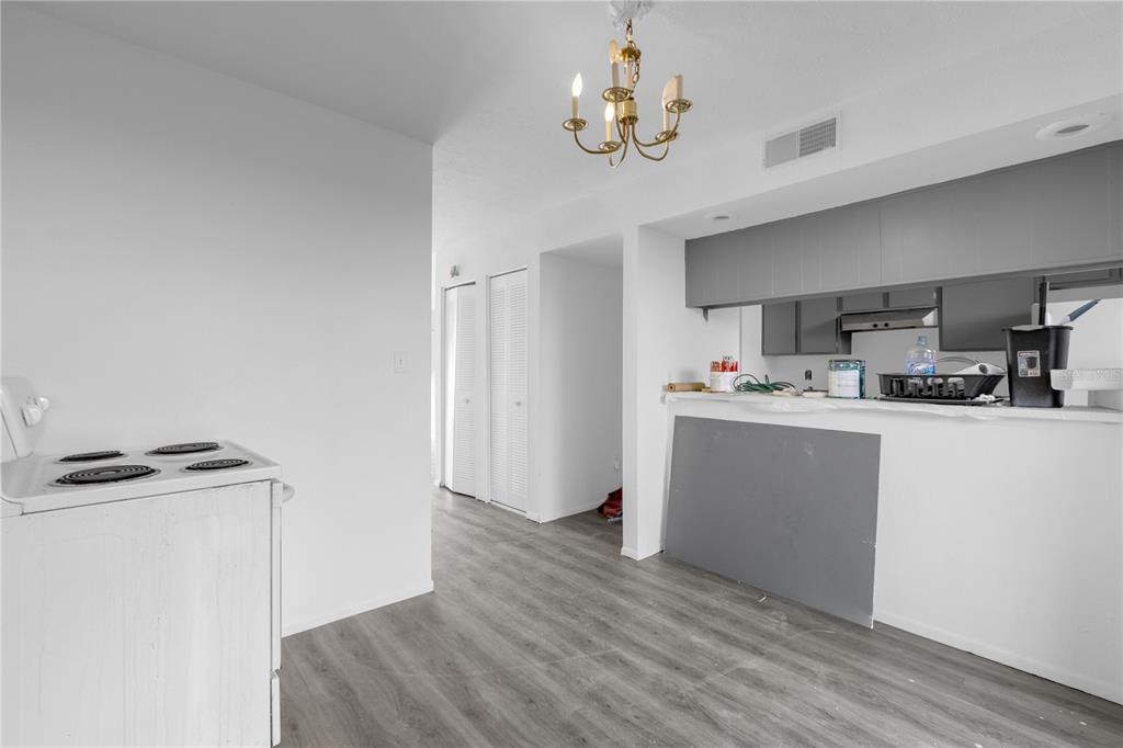 A kitchen area features gray cabinets, a white stove, and light wood-look flooring — 4025 BILLINGSGATE ROAD UNIT 2004, ORLANDO, FL
