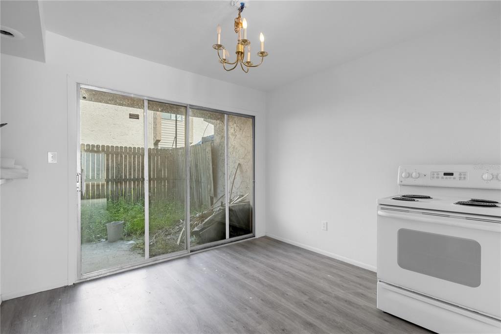A dining area with wood-look flooring, a sliding glass door, and a white electric stove — 4025 BILLINGSGATE ROAD UNIT 2004, ORLANDO, FL