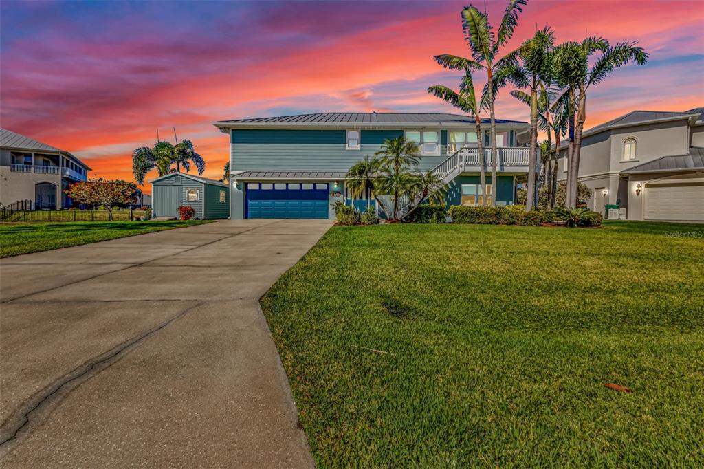 A two-story house with blue siding and a large driveway under a sunset sky — 4255 SPIRE STREET, PORT CHARLOTTE, FL
