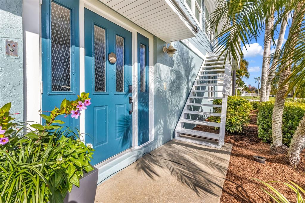A blue front door with glass panels sits next to white exterior stairs and landscaping — 4255 SPIRE STREET, PORT CHARLOTTE, FL
