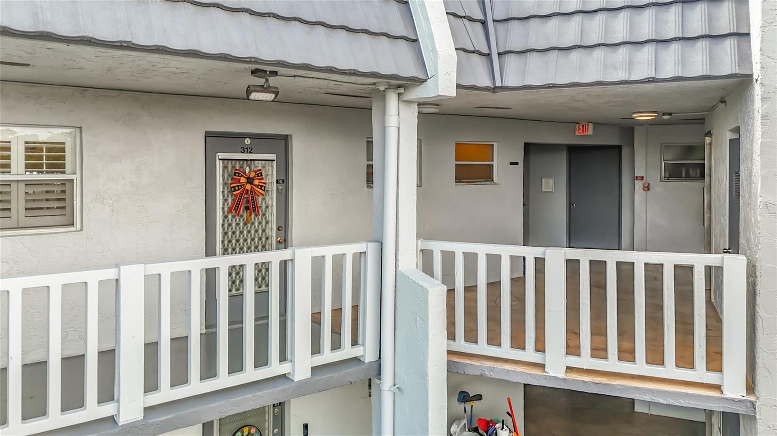 An exterior view of a multi-story apartment building with white railings and gray doors — 6570 Royal Palm Boulevard # 312, Margate FL 33063, MARGATE, FL