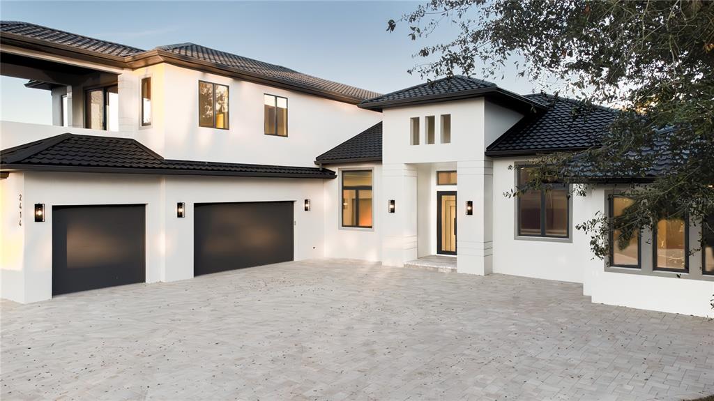A modern two-story house features a white stucco exterior, black roof tiles, and a paved driveway — 2414 BAYSHORE ROAD, NOKOMIS, FL