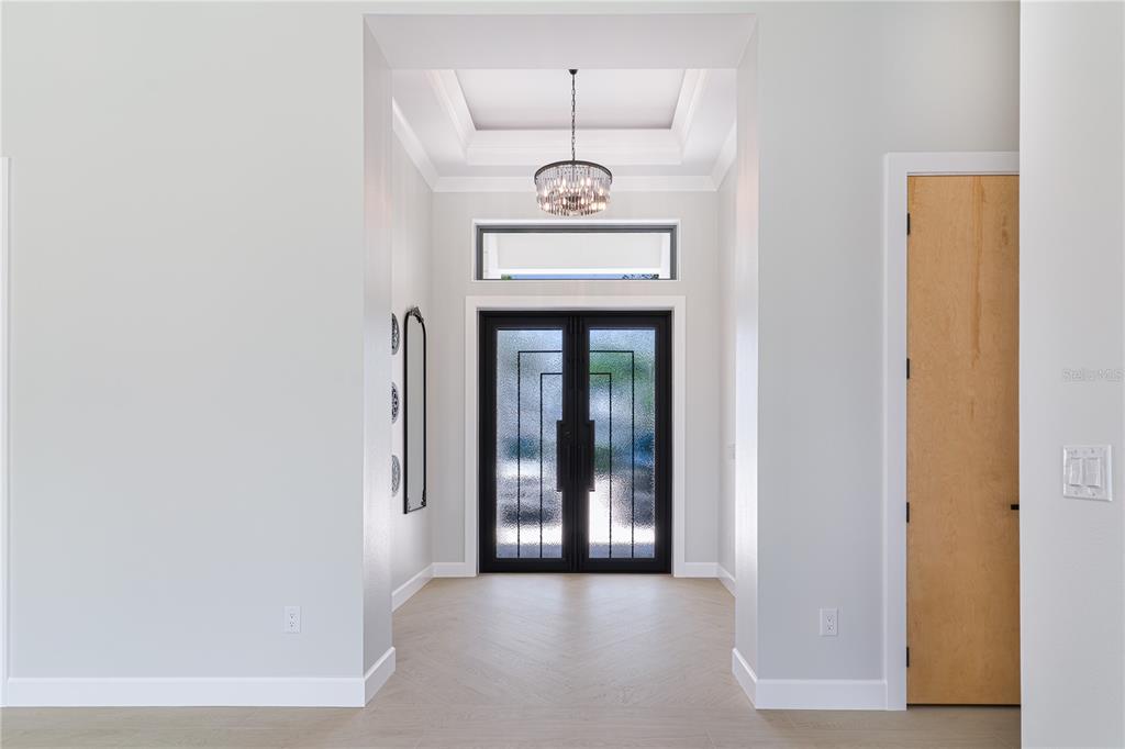 A bright entryway features a double glass door, a tray ceiling, and light wood flooring — 2414 BAYSHORE ROAD, NOKOMIS, FL