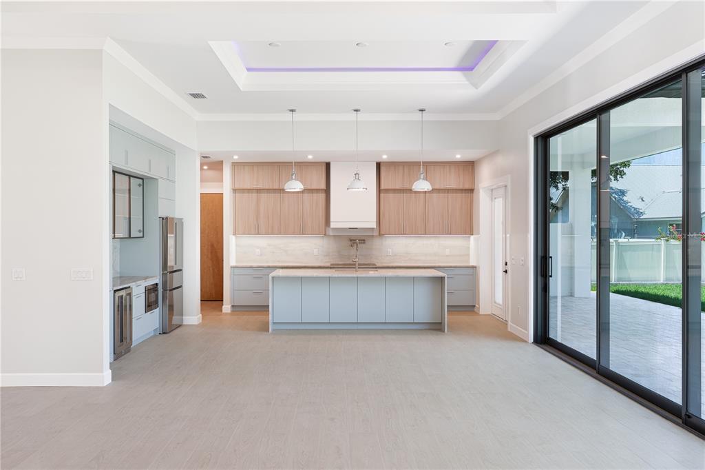 A modern kitchen features light wood cabinets, a gray island, and a tray ceiling — 2414 BAYSHORE ROAD, NOKOMIS, FL