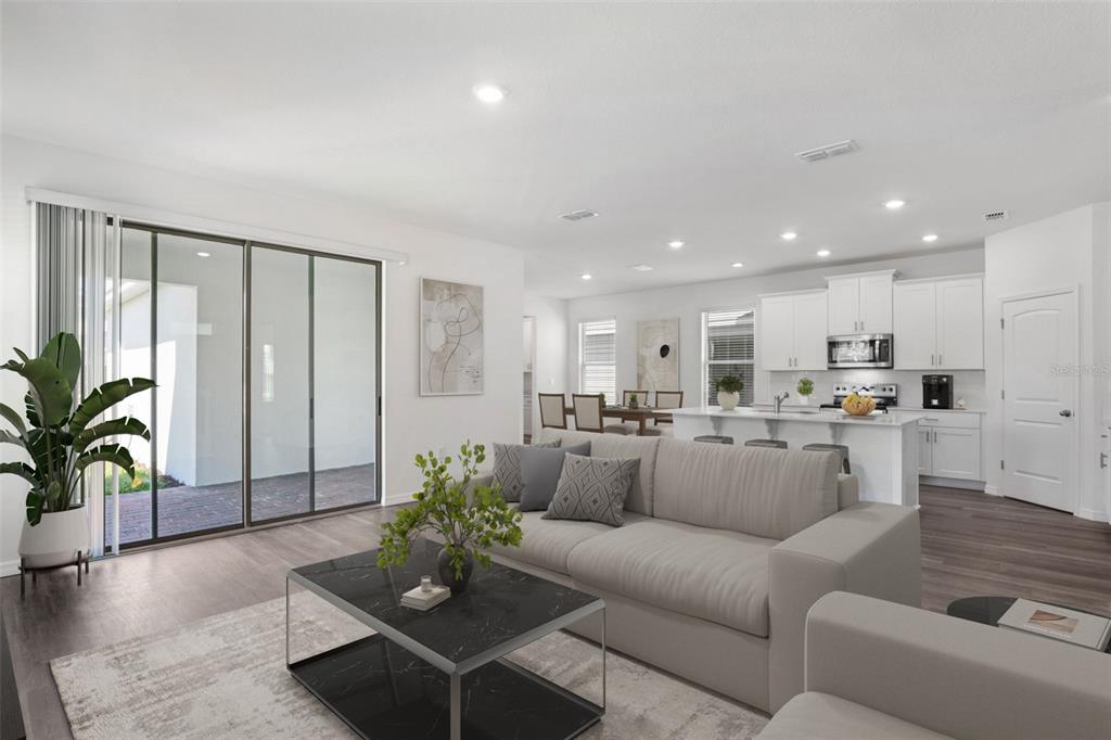 A modern open-concept living room and kitchen featuring white cabinetry, a marble-topped island, and sliding doors — 11864 SHINE VIEW LANE, WINTER GARDEN, FL