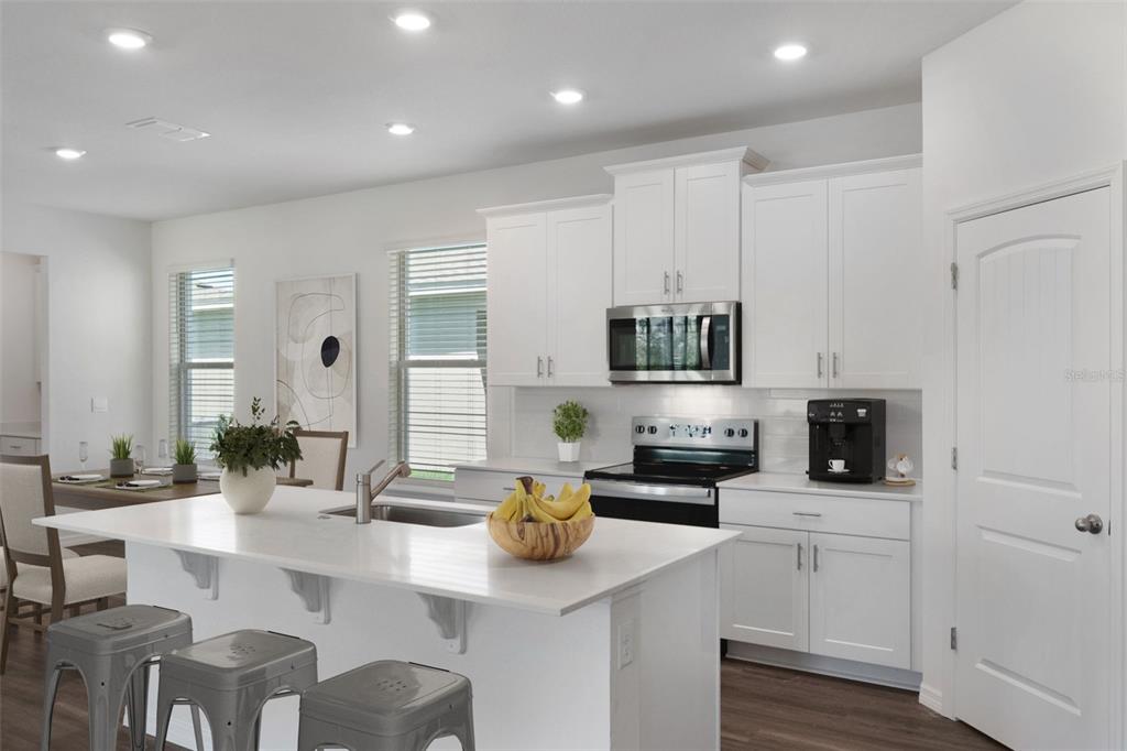 A modern kitchen features white cabinets, a large island with seating, and stainless steel appliances — 11864 SHINE VIEW LANE, WINTER GARDEN, FL