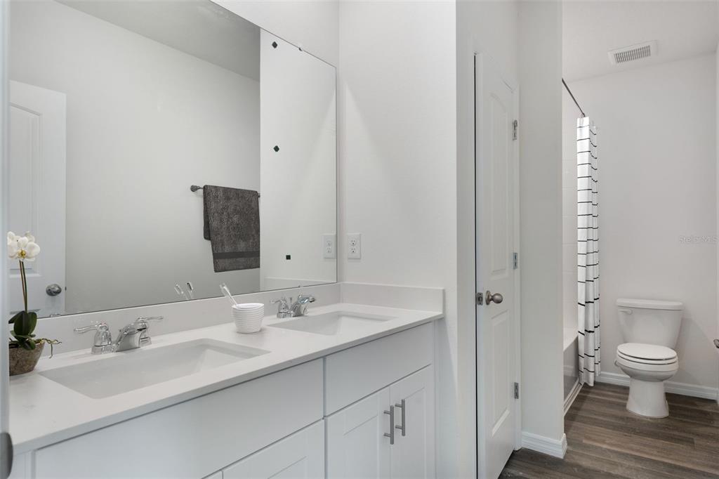 A bathroom features a double vanity with white cabinets, a large mirror, and a toilet — 11864 SHINE VIEW LANE, WINTER GARDEN, FL