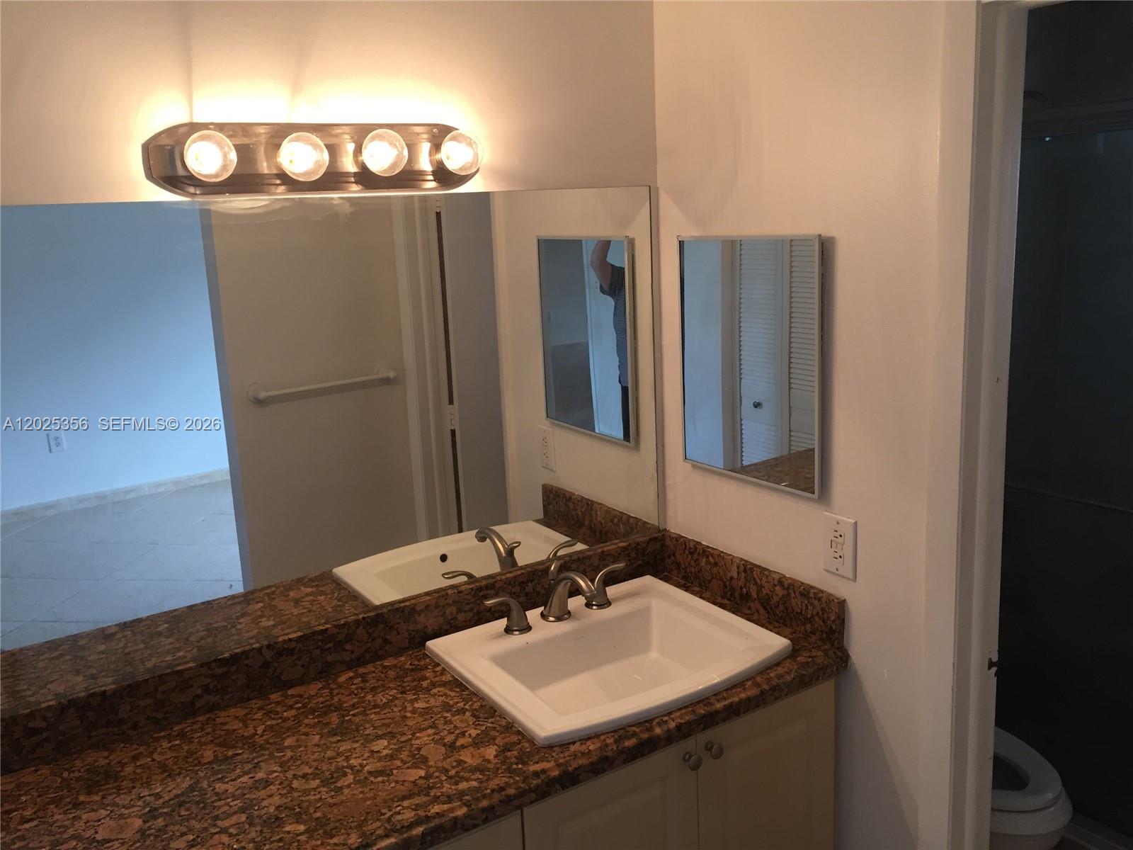 An empty room features beige tile flooring, a vaulted ceiling, and an arched doorway — 15570 SW 76th Ln # 9, Miami FL 33193, MIAMI, FL