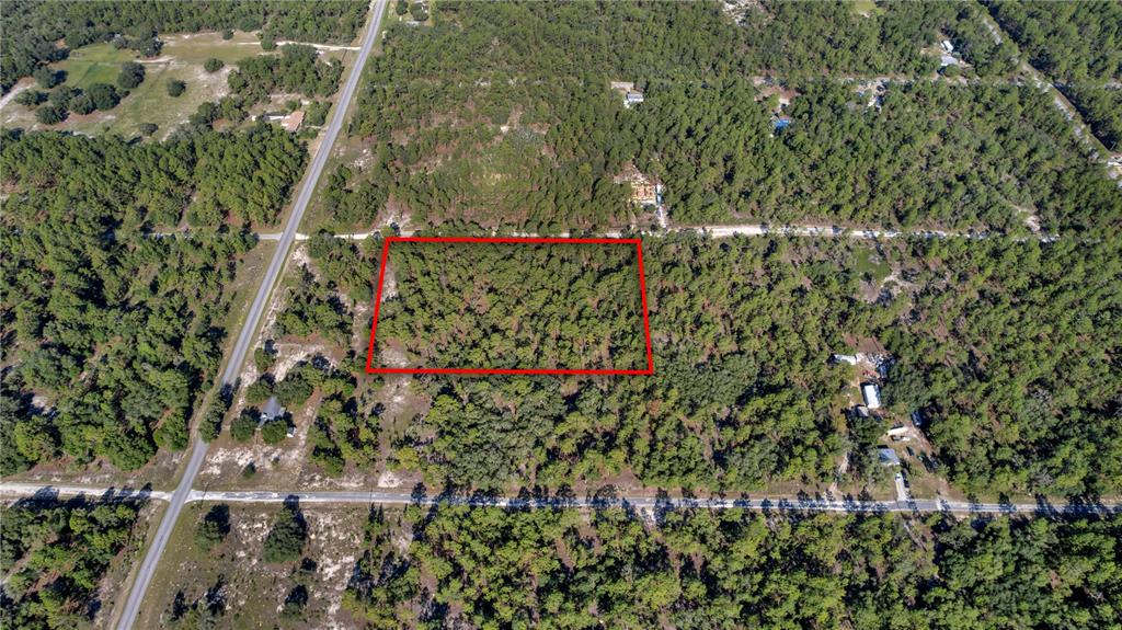 An aerial view shows a rectangular plot of land outlined in red amidst wooded terrain — LOTS 16 AND 17 SE 130TH CT, DUNNELLON, FL